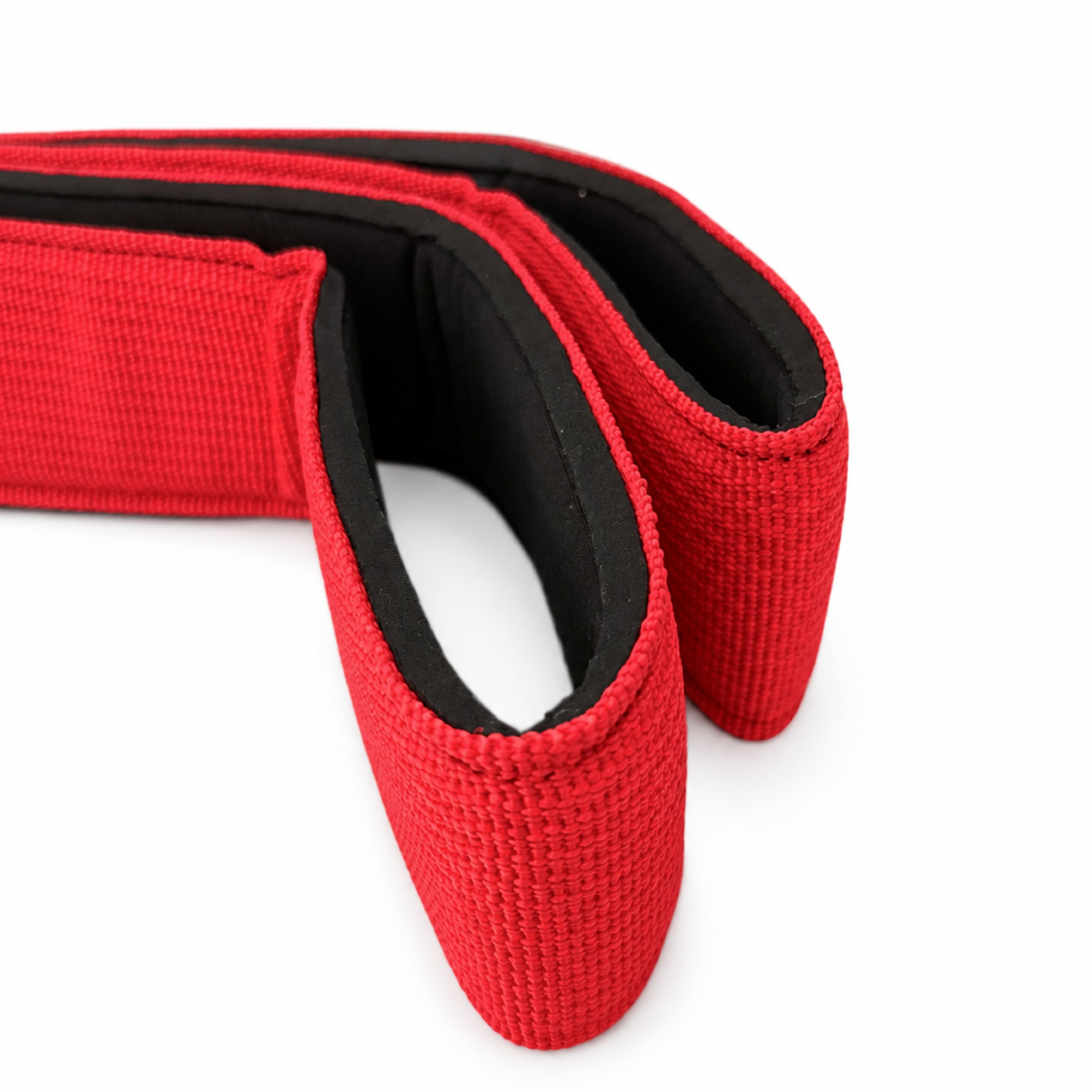 Close-up of a red textured strap or belt with a black inner lining, photographed on a clean white background.