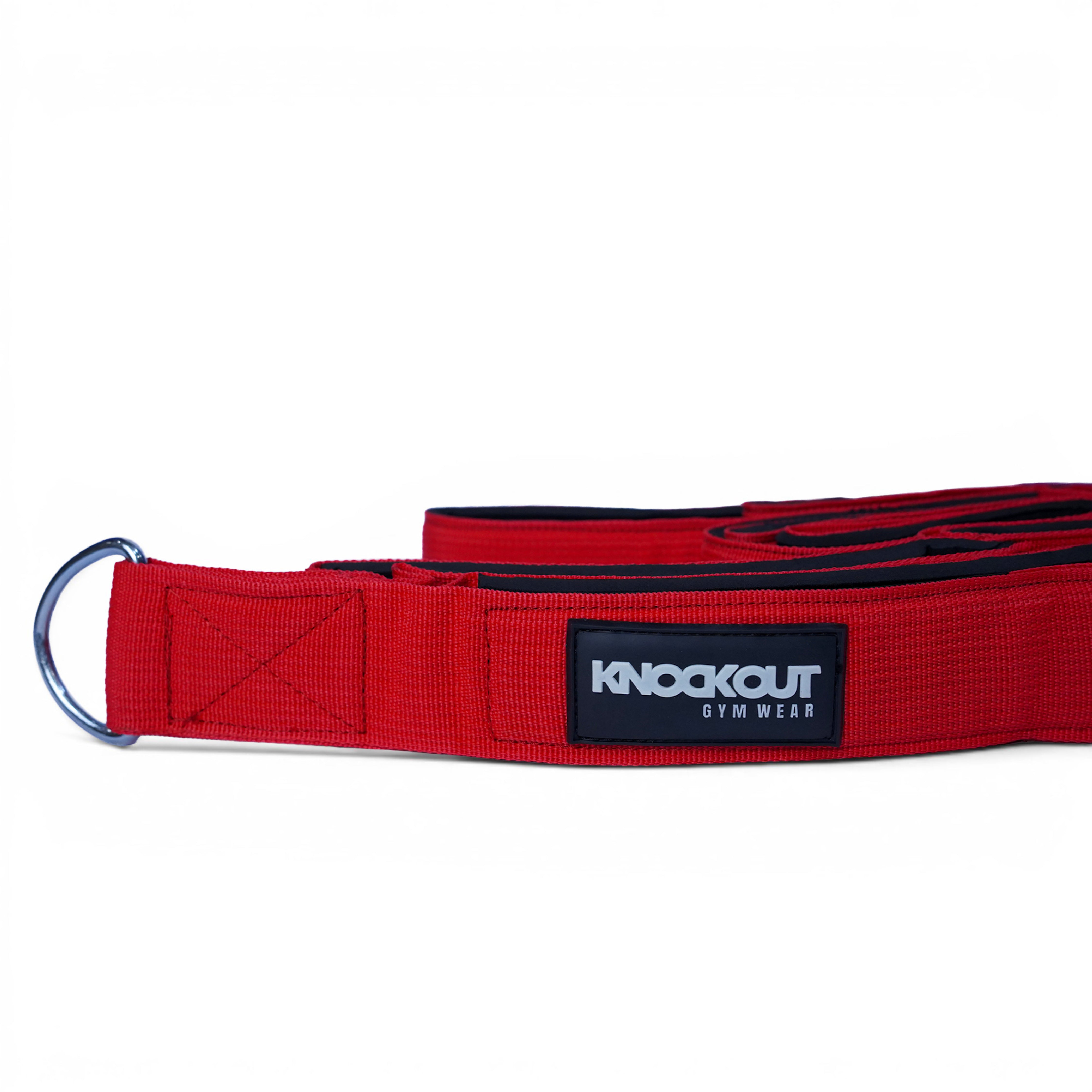 A red webbing weightlifting belt with a silver metal D-ring and a black brand patch reading 'KNOCKOUT GYM WEAR'.